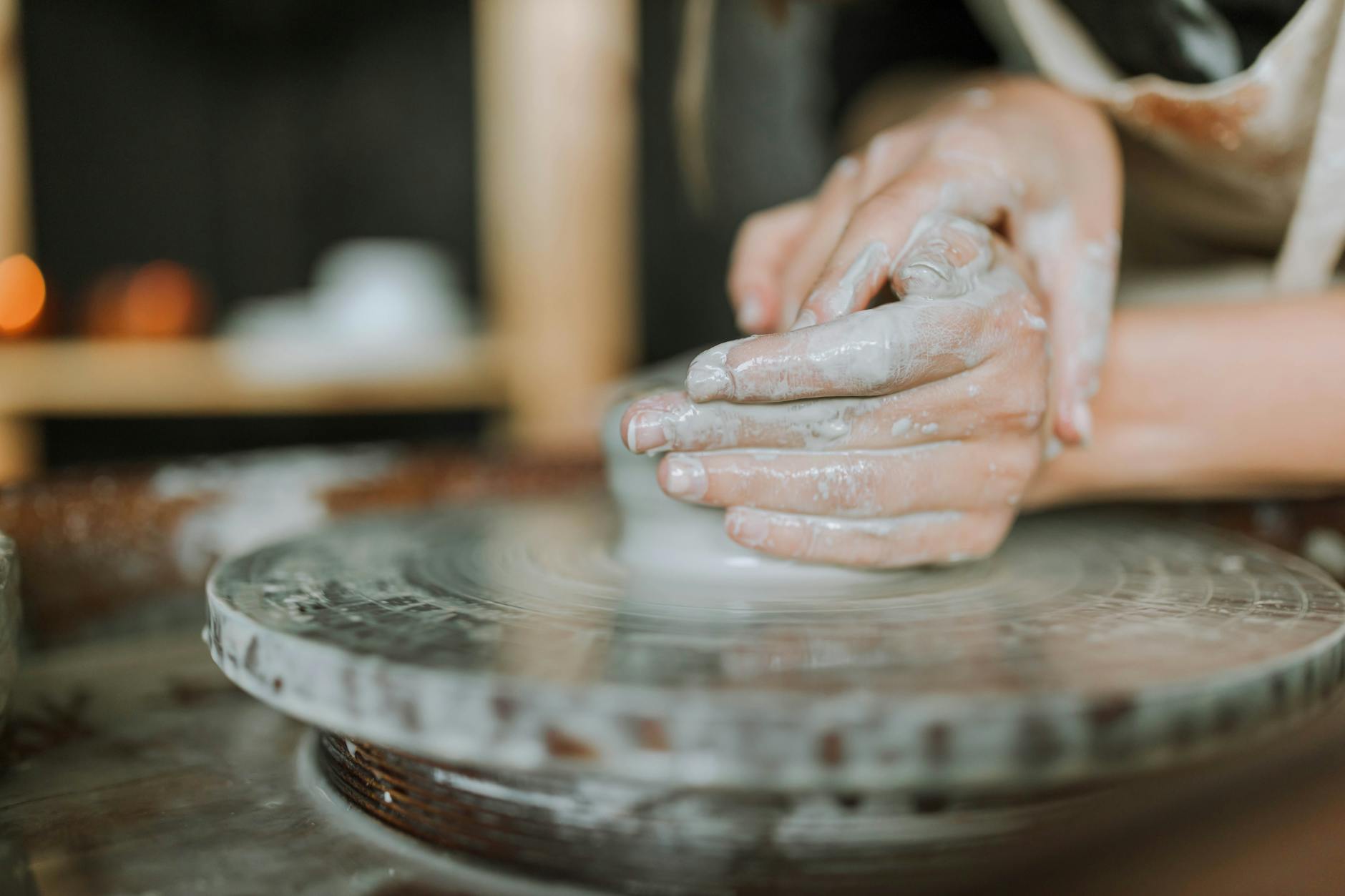 hands making clay pot on brown wooden table