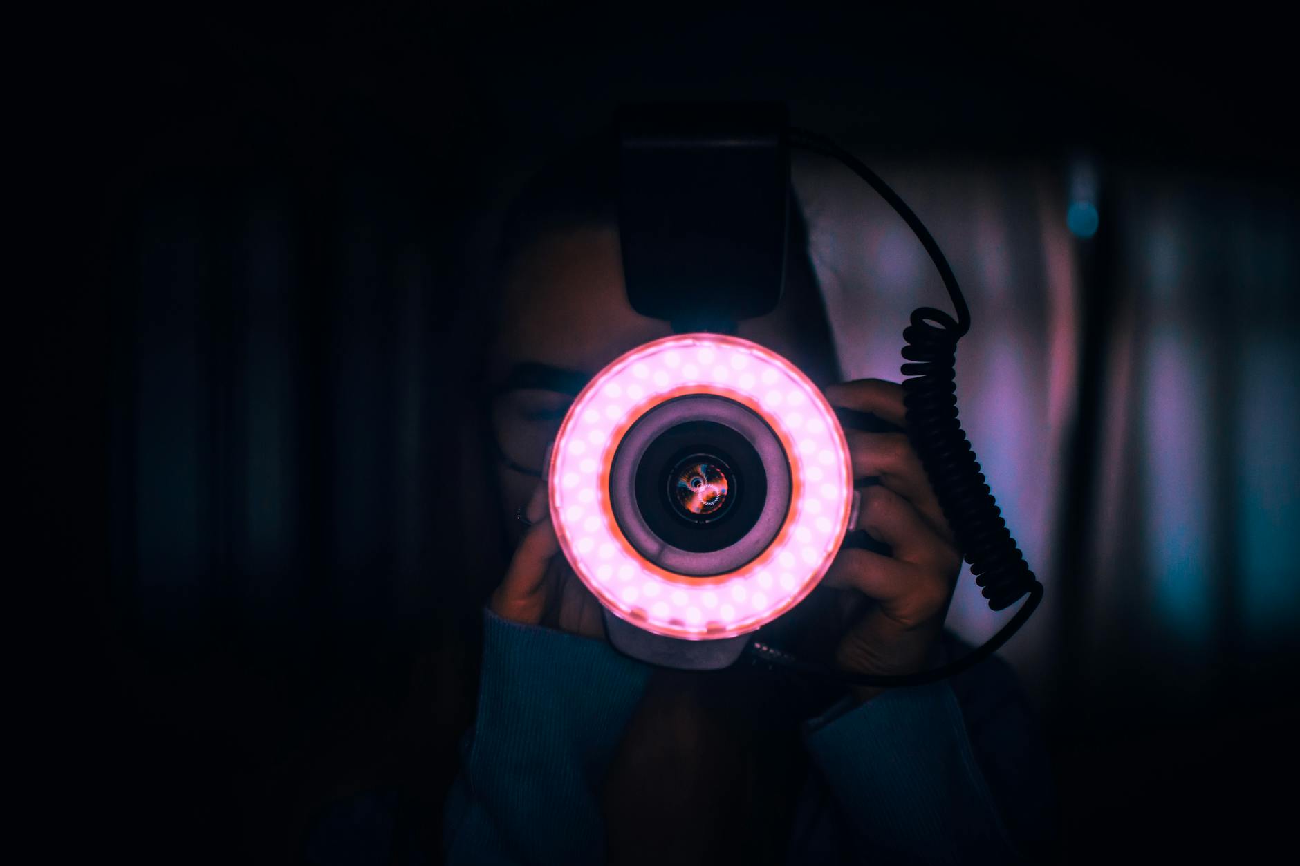 person holding camera with red lights on lens