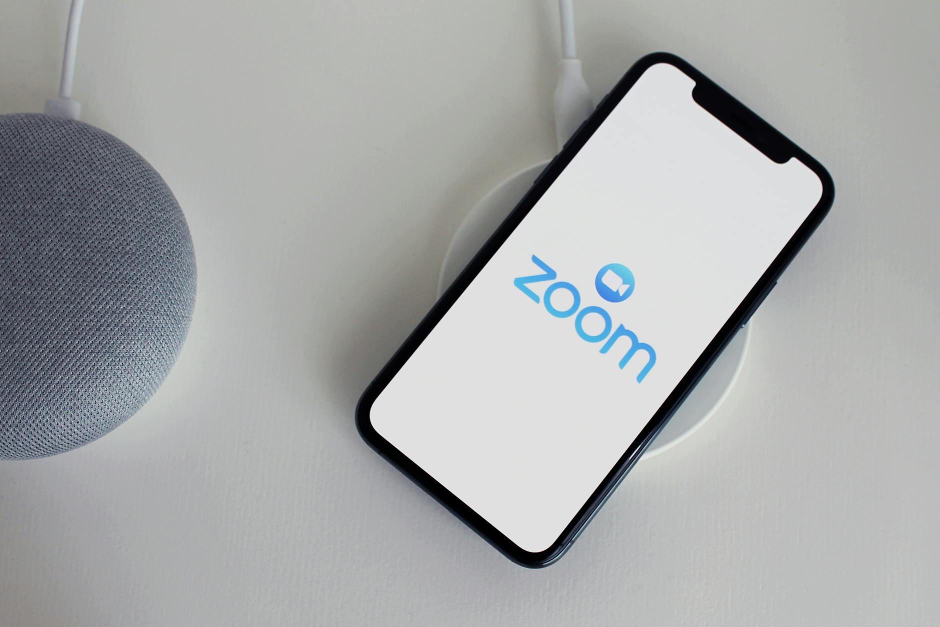 a cellphone on a wireless charger beside a portable speaker